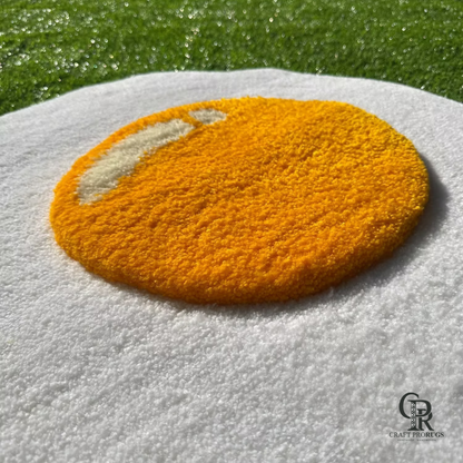 Corner close-up of fried egg rug showing tufted white edge and a portion of the yolk on grass