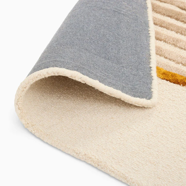 Folded corner view of Aurel Gold Line Rug hand tufted wool rug showing thickness and backing.