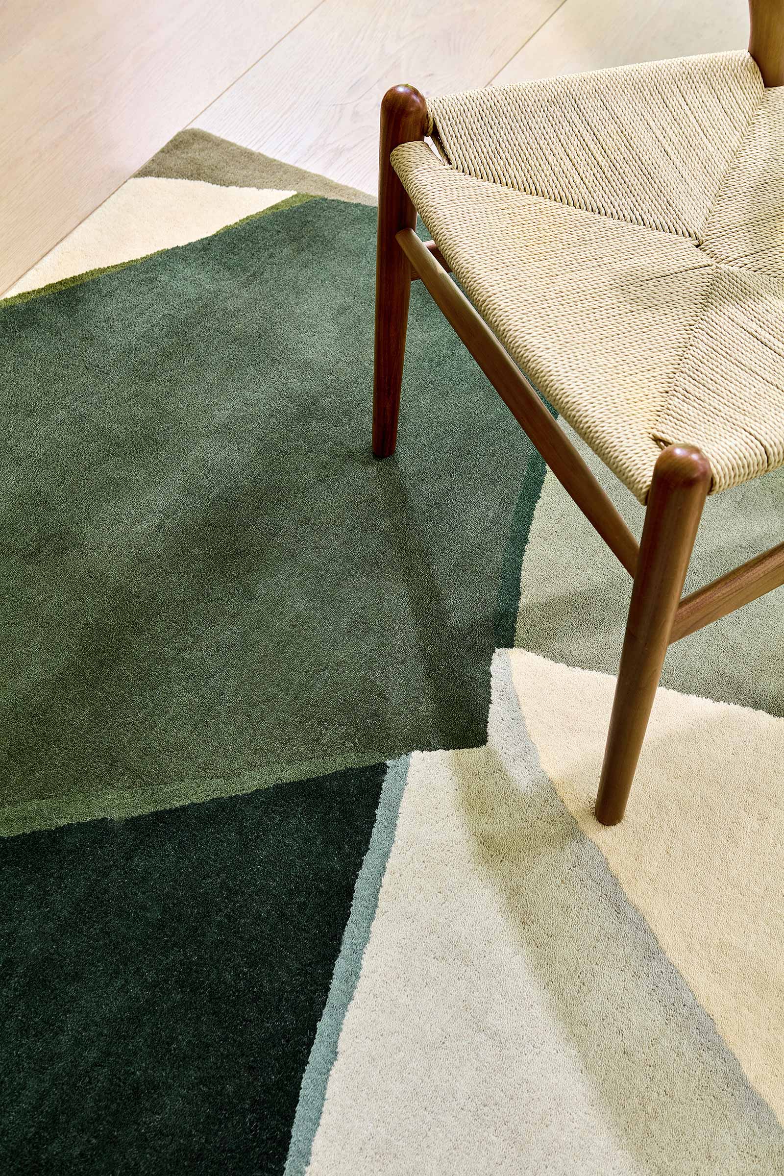 Close up corner detail of Harlequin Sumi hand tufted wool rug showing texture and geometric pattern beside chair.