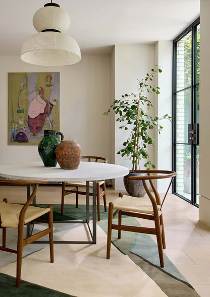 Harlequin Sumi hand tufted wool rug styled in modern living room interior with green abstract design.