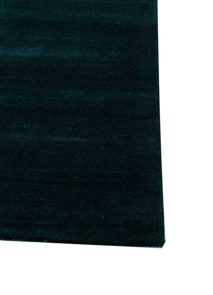 Corner view of hand tufted wool rug showing abstract layered wave design, rich colors and fine edge detailing.