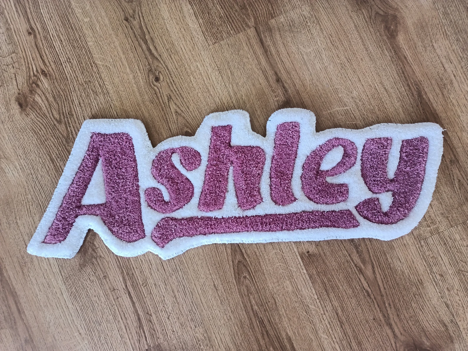Purple tufted custom rug featuring the name ‘Ashley’ on a wooden floor