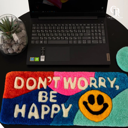 op view of Be Happy Desk Rug showing colorful rainbow design and tufted happy message for positive desk vibes