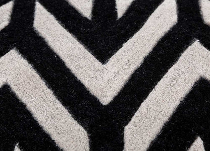 Close view of hand tufted wool rug highlighting soft pile texture and bold black ivory chevron pattern.