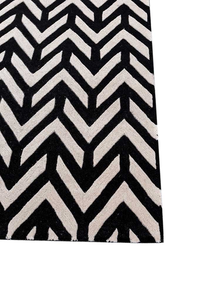 Corner detail of hand tufted wool rug with sharp chevron zigzag design in black and ivory colors.