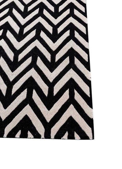 Corner detail of hand tufted wool rug with sharp chevron zigzag design in black and ivory colors.