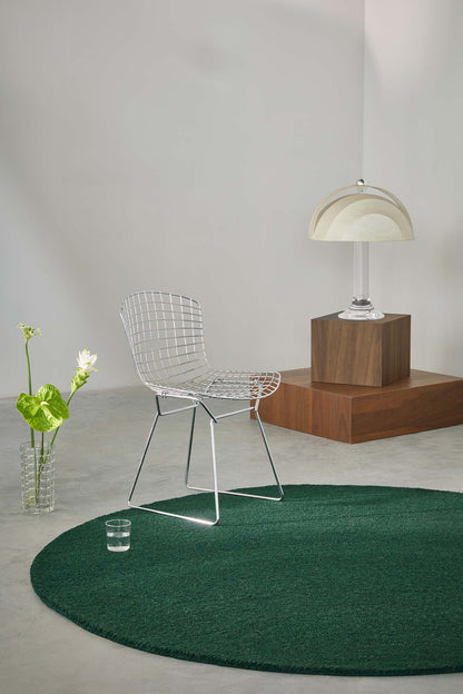 Echo Forest Solid hand tufted wool rug placed in a minimal interior highlighting natural green tone and solid design.