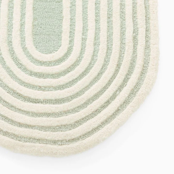 Close view of Elora Sage Oval hand tufted wool rug highlighting curved line pattern and sage green texture.