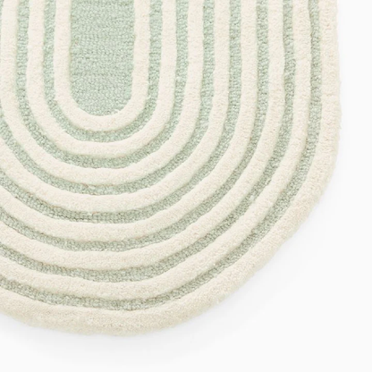 Close view of Elora Sage Oval hand tufted wool rug highlighting curved line pattern and sage green texture.