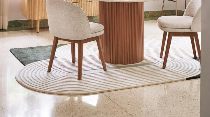 Elora Sage Oval hand tufted wool rug styled in a modern room setting under dining chairs.