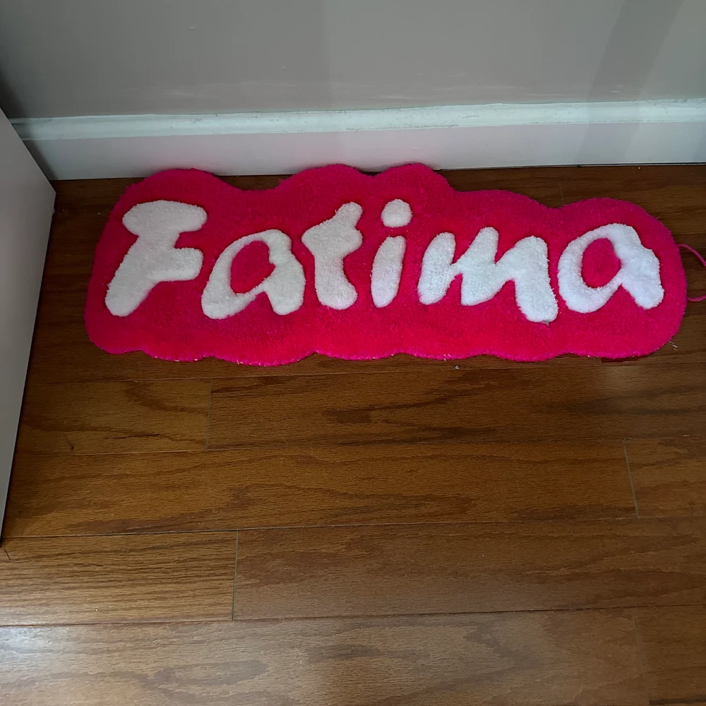 Red custom name rug with ‘Fatima’ text on a wooden floor