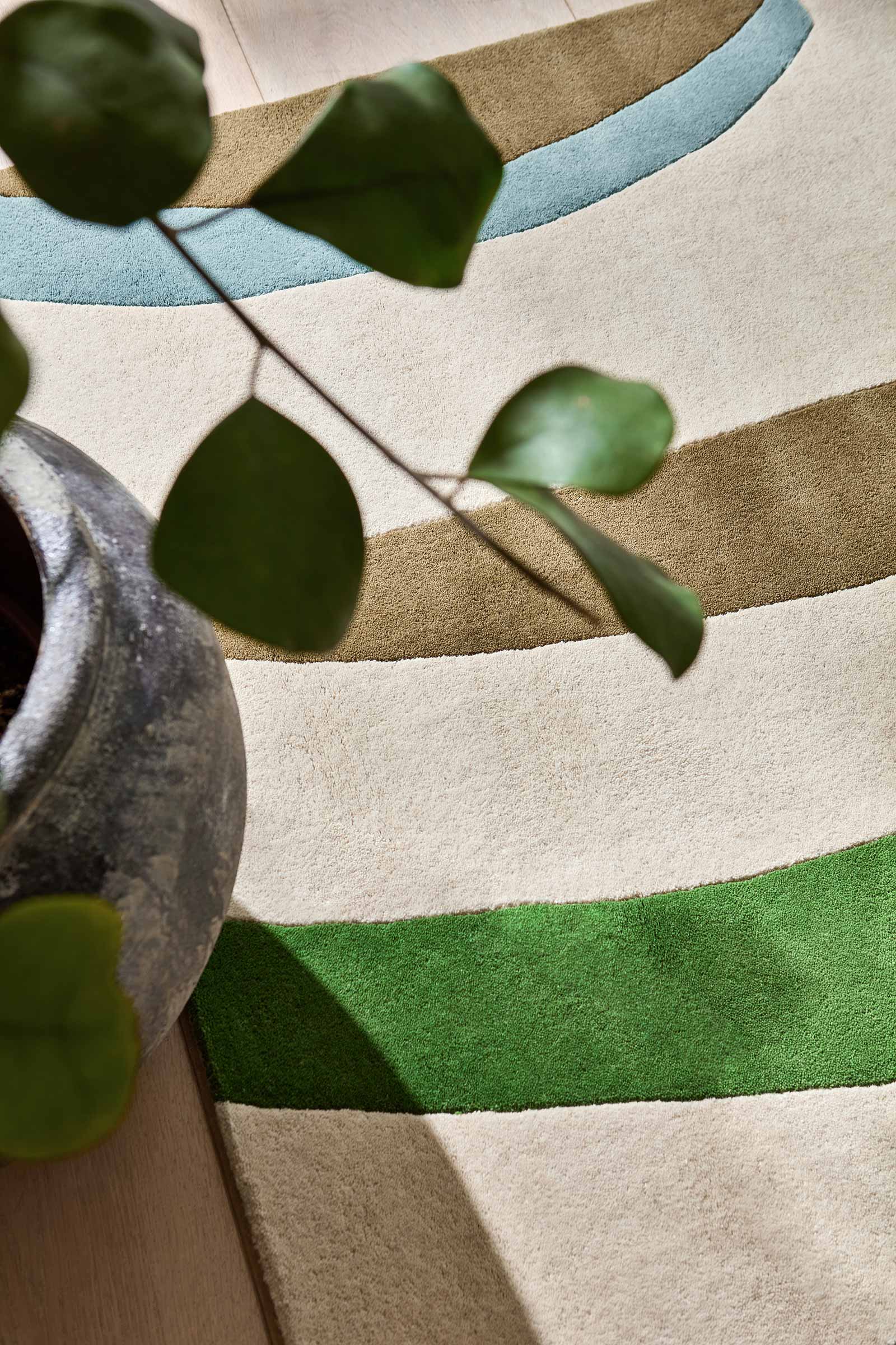 Styling detail view of Harlequin Torillo hand tufted wool rug showing abstract pattern with decor elements for scale