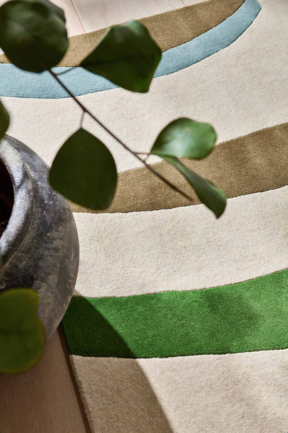 Styling detail view of Harlequin Torillo hand tufted wool rug showing abstract pattern with decor elements for scale