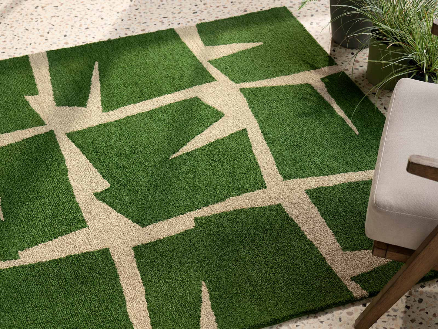 Moqui Green hand tufted wool rug placed under seating showcasing abstract geometric layout and rich green wool texture.