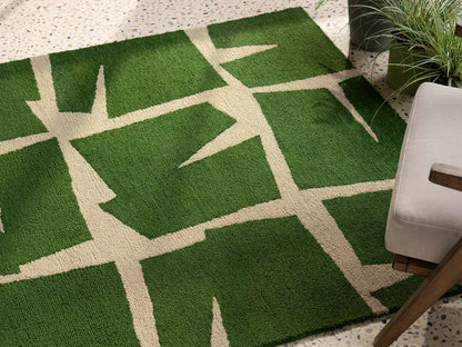 Moqui Green hand tufted wool rug placed under seating showcasing abstract geometric layout and rich green wool texture.