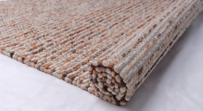 Side-angle view of Pebbles Copper flatweave rug highlighting thin flatweave profile, textured pattern, and warm copper tones