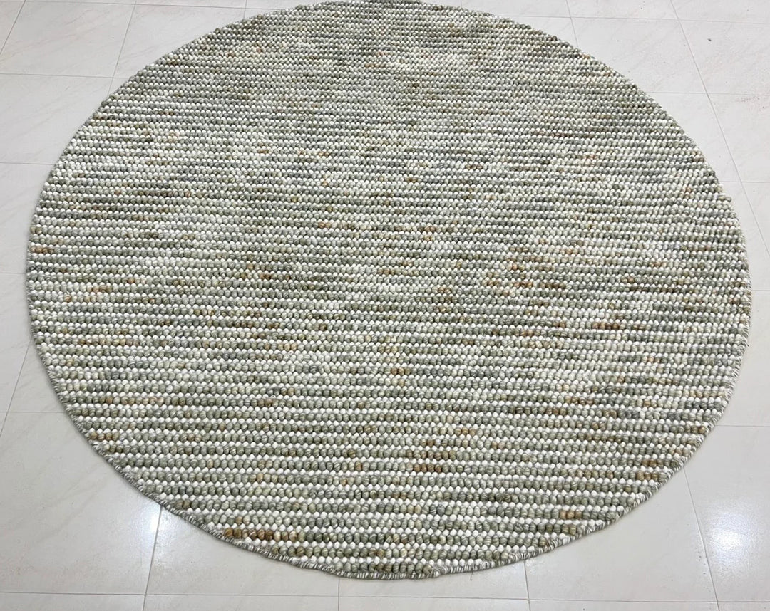 Pebbles Sage Green round flatweave rug in living room setup adding style and warmth to the space.