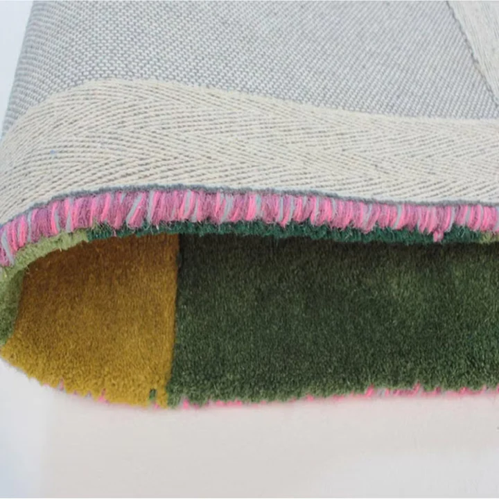 Corner folded view of pixelia spectrum hand tufted wool rug highlighting thickness quality backing and craftsmanship.