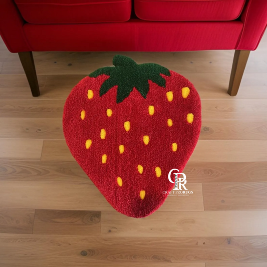 Strawberry shaped hand-tufted rug front view on wooden floor showing red base with yellow seeds and green leaf top.