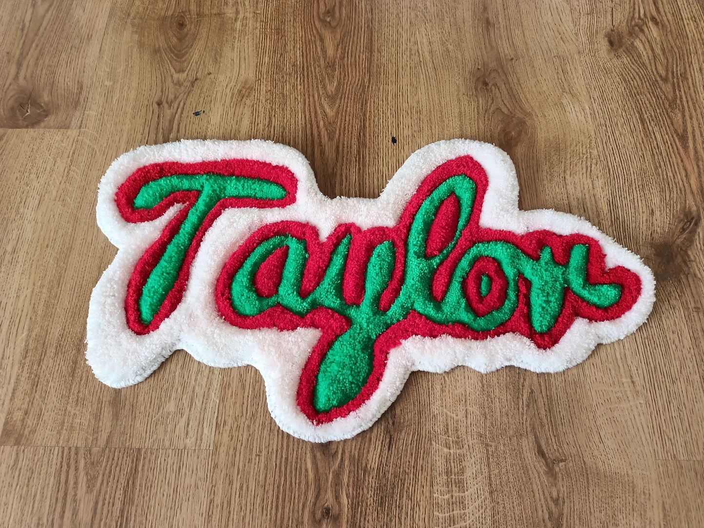 Green and red custom name rug with ‘Taylor’ text on a wooden floor