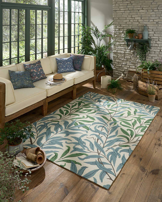 Willow Leafy Arbour hand tufted wool rug styled in a cozy living room featuring leafy botanical pattern in soft green tones.