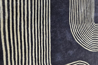 lose view of Xosi Noir Linear hand tufted wool rug highlighting dense linear detailing and contrast of gold lines on dark wool base.